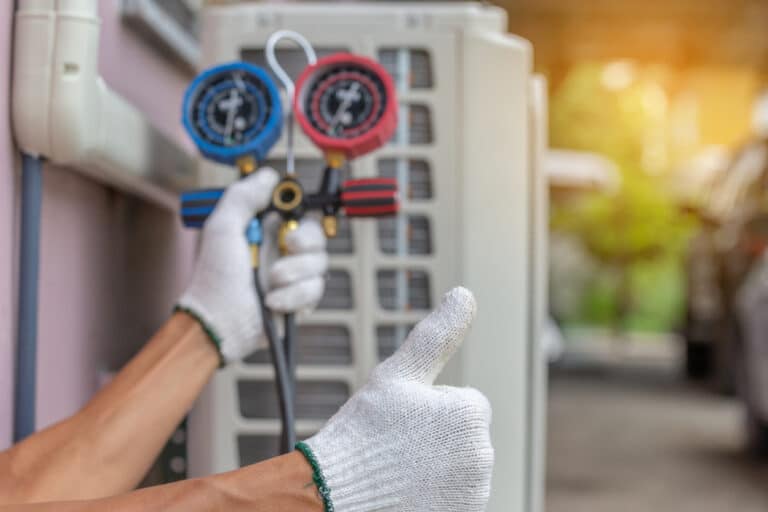 Close up of air conditioning technician holding a thumbs up sign while inspecting an AC