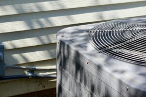 An HVAC system sits outside of a home, with the pipe controlling air flow going into the house