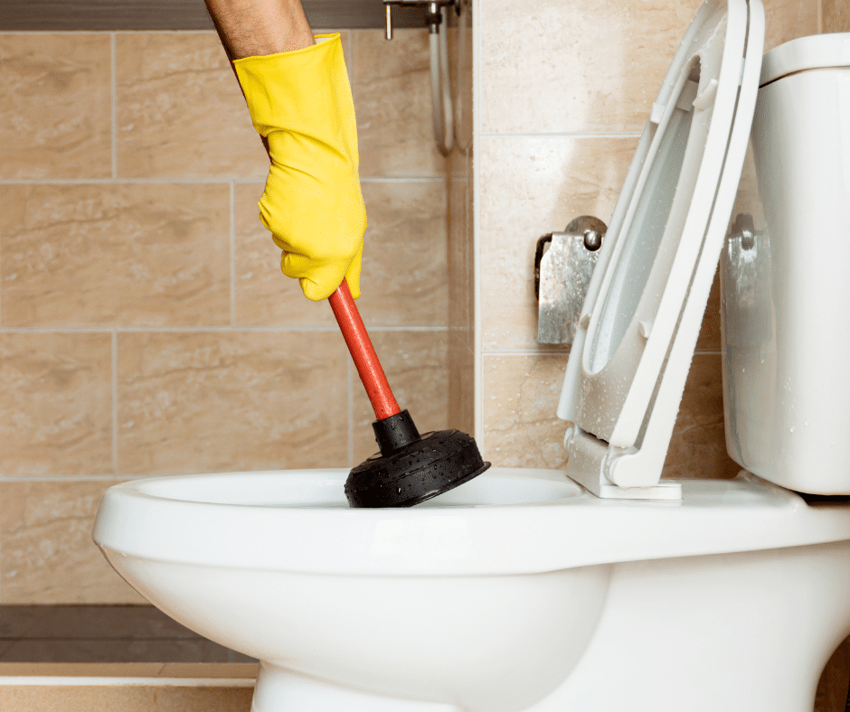 A gloved hand inserts a plunger into a toilet