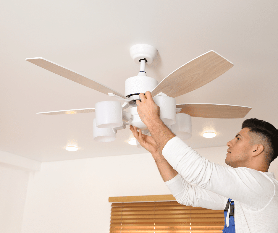 An electrician installs a ceiling fan