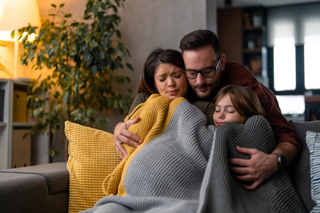 Family huddling under a blanket with broken furnace i the winter