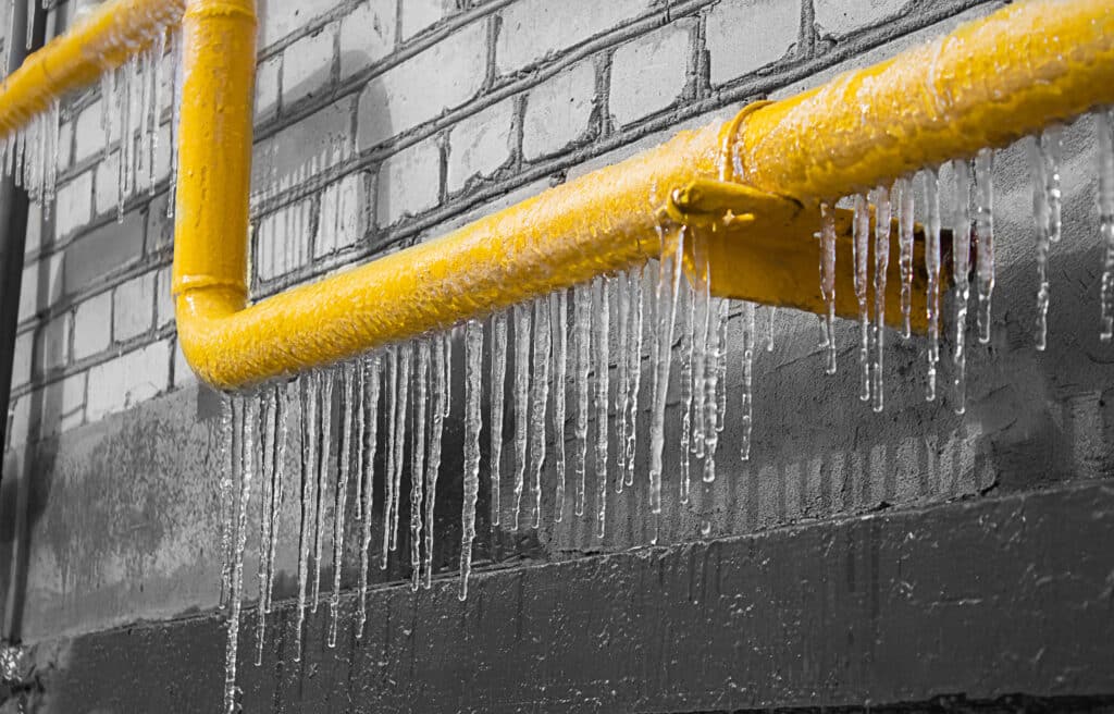 Frozen yellow pipe against wall